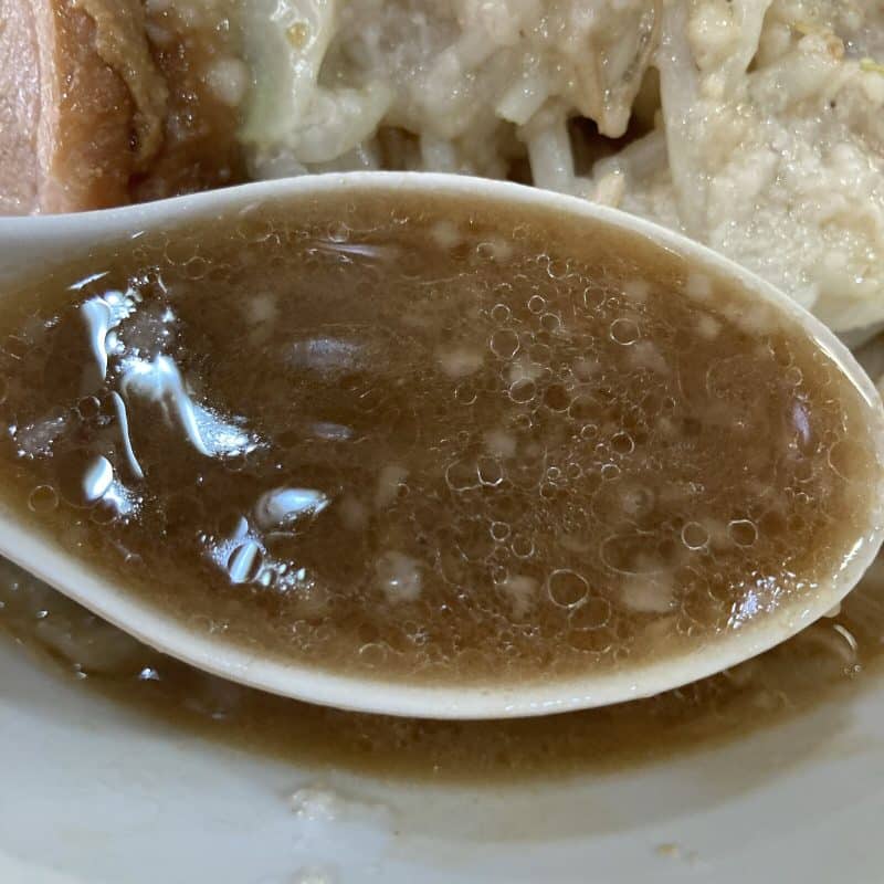 豚レンジャーのラーメン ミニの乳化したスープをレンゲですくう