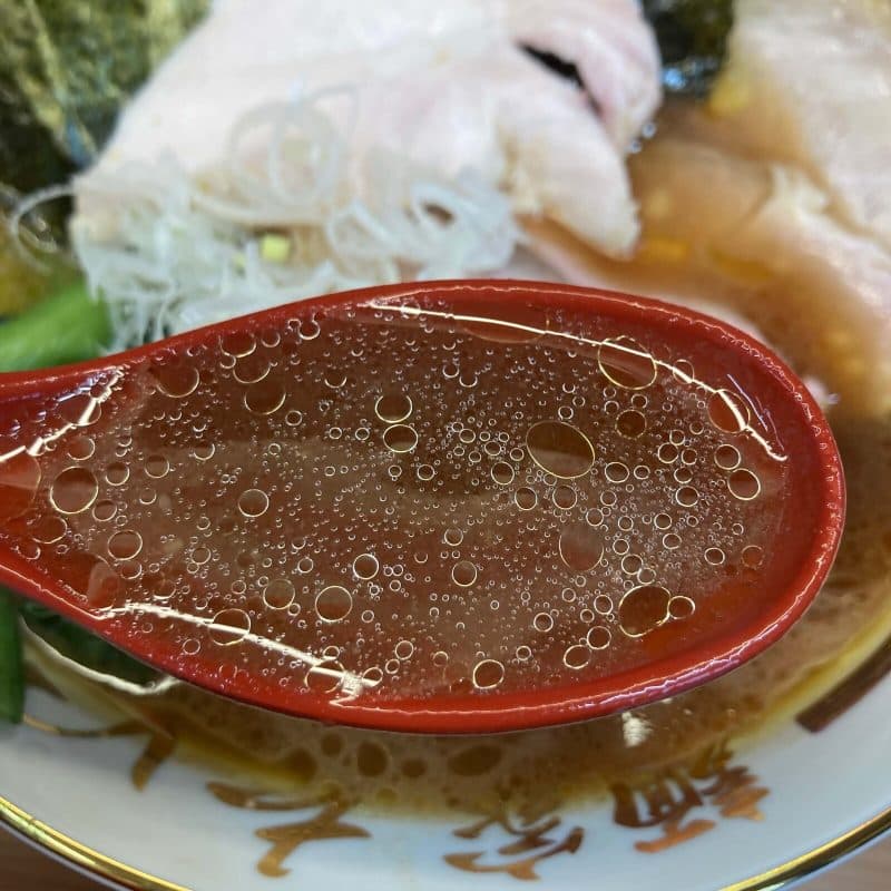 【麺家 たいせい】の豚骨醤油スープを赤いレンゲで