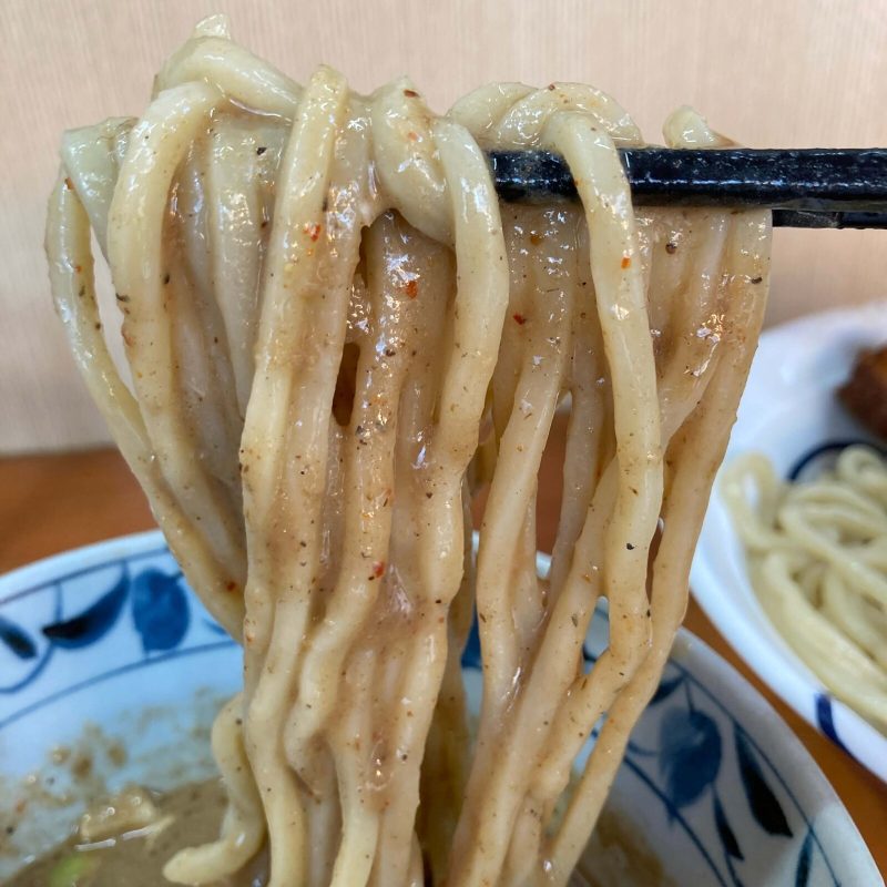 【自家製麺 福は内】の麺をつけ汁に潜らせて持ち上げ