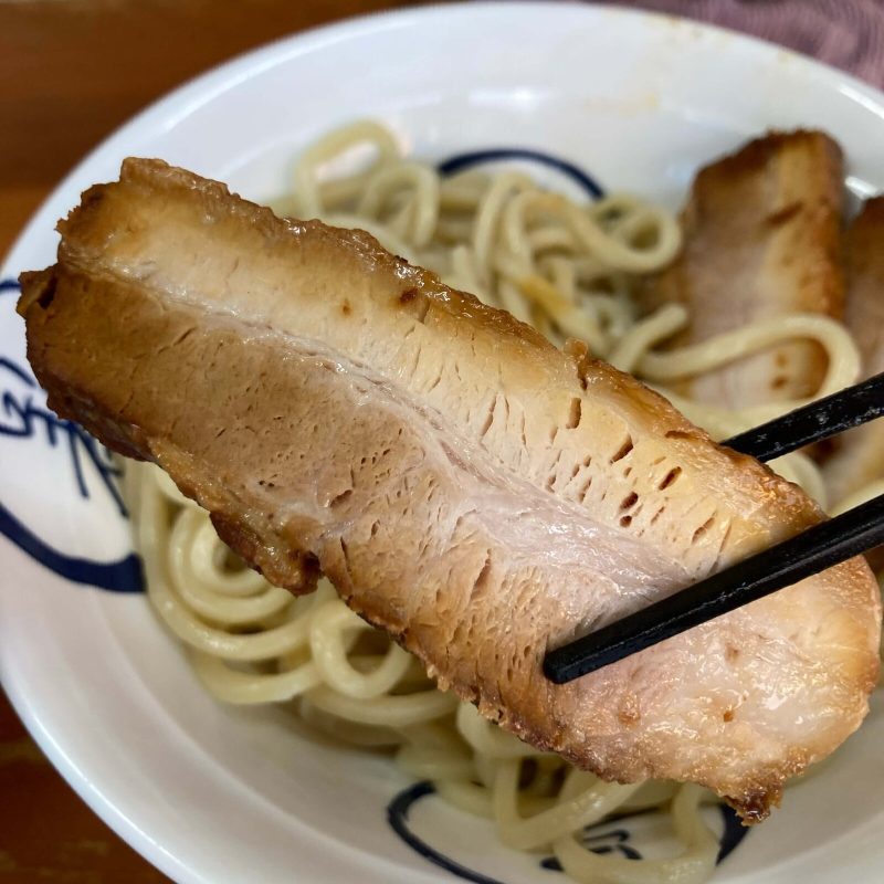 【自家製麺 福は内】の半肉のチャーシューを箸で掴む