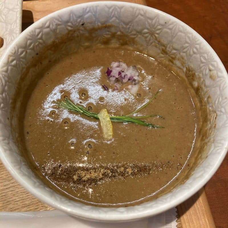 与野【御影麺 鏑矢】の豚骨魚介のつけ汁 紫玉ねぎとハーブ乗せ