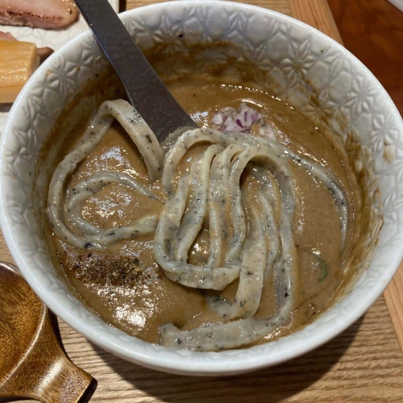 与野【御影麺 鏑矢】のつけ汁に極太麺を浸す