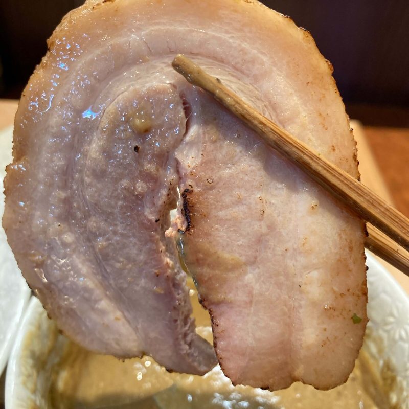 与野【御影麺 鏑矢】の豚バラチャーシューを箸で持ち上げる