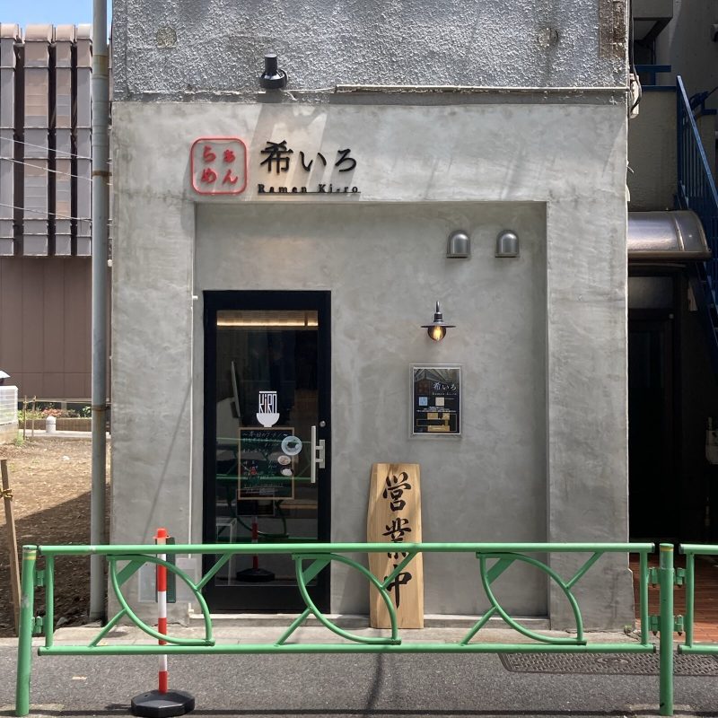 中野坂上【らぁめん 希いろ】の外観 灰色の壁に赤い店名ロゴと「営業中」の木札